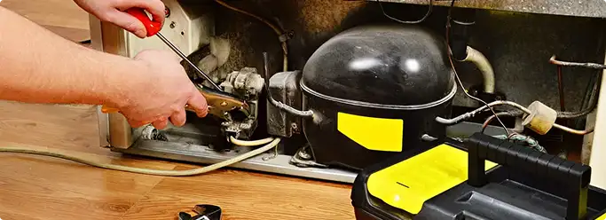 Refrigerator repair technician fixing the compressor and wiring in Hermitage, TN