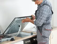 Appliance repair technician installing a built-in cooktop in Nashville, TN