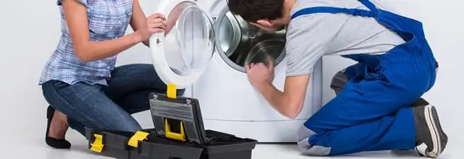 Washer repair technician inspecting a front-load washing machine with tools in Nashville, TN