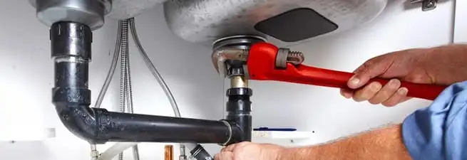 Garbage disposal repair technician tightening the sink drain and disposal connection in Nashville, TN