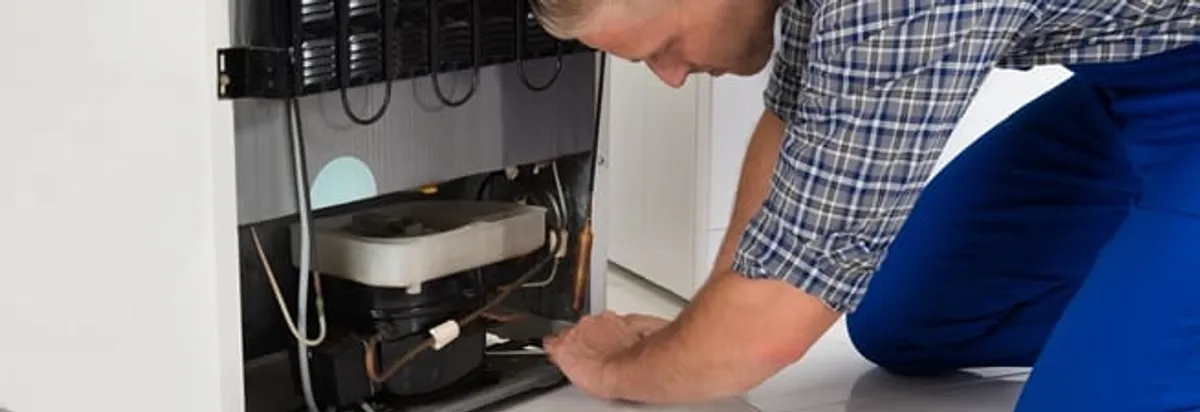 Refrigerator repair technician servicing the compressor and condenser area in Nashville, TN