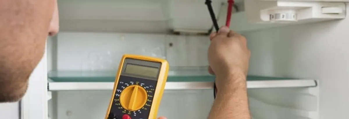 Refrigerator repair technician testing electrical components with a multimeter in Nashville, TN