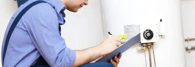 Water heater repair technician inspecting the unit and recording service notes in Nashville, TN